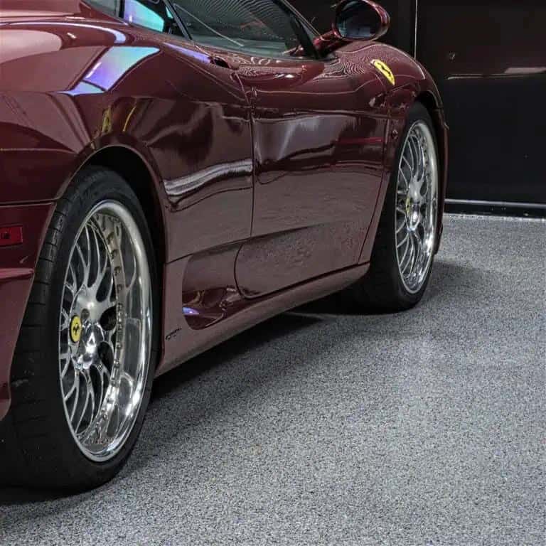 Red sports car sits atop a full flake epoxy and polyaspartic concrete coating.
