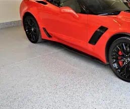Red sports car sits atop a full flake mica epoxy polyaspartic coated floor.